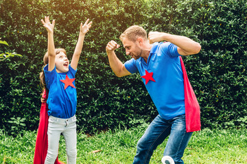 Father with little daughter in superhero costume having fun and playing superheroes together at park outdoors.Love of family and father day concept