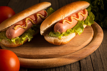 Photo of barbecue grilled hot dog with yellow mustard and ketchup on wooden background. Hot dog...