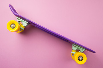 purple youth skateboard on pink background. children's plastic mini cruiser board. concept: healthy lifestyle, sport, movement. minimalism, flat lay, copy space