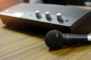 Microphone with mini power amplifier on wooden table.