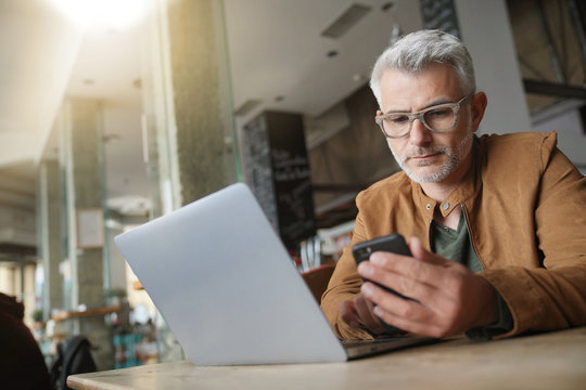 Middle-aged man in trendy restaurant using smartphone