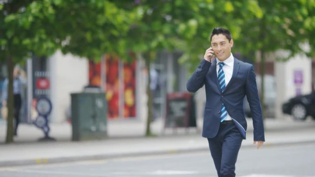 Attractive man in a suit talking on his phone in the city and celebrating at something