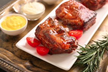 Plate with delicious grilled ribs on metal tray
