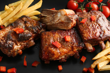 Delicious grilled ribs with french fries on plate, closeup