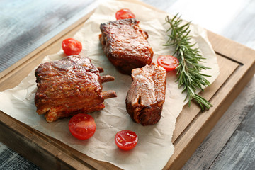Delicious grilled ribs with tomatoes on wooden board
