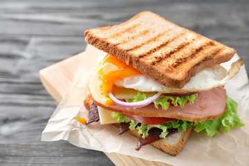 Tasty sandwich with egg on wooden table