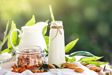 Almond and almond milk on a wooden table in the summer garden. Useful food.