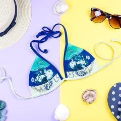 Fototapeten Summer holiday background. Tropical summer concept with fashion accessories, bikini, leaves on bright background. © Maria Shchipakina