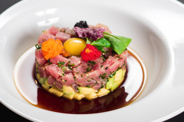 Tasty tartar salad on black background