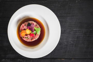 Tasty tartar salad on black background