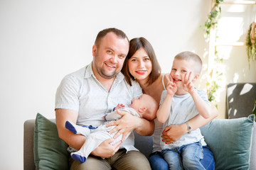 Image of smiling parents with two young sons sitting on sofa