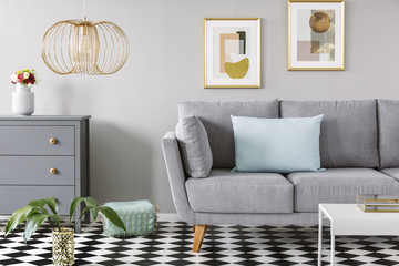 Light blue pillow placed on grey couch in bright living room interior with checkerboard linoleum...