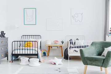 Bright scandinavian style bedroom interior with two metal frame kid's beds, one white, one black,...