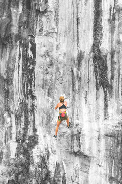 Young woman climbing up a cliff, copy space