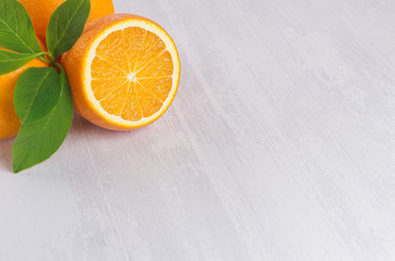 Bright slice oranges closeup texture and green leaves on white wood background, top view.