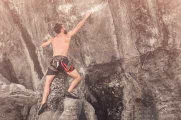 Young bearded man climbs the cliff without a safety rope. Toned