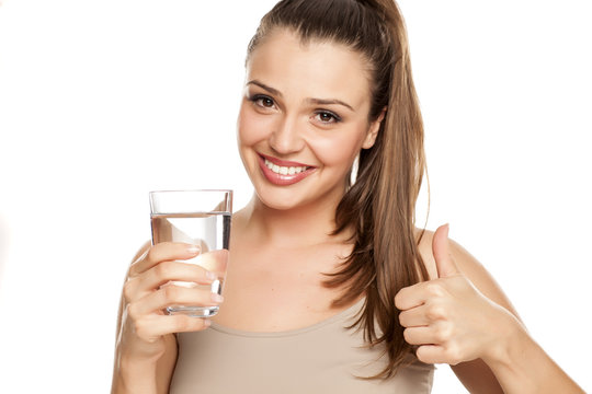 happy woman holds a glass with water and showing thumbs up on white background