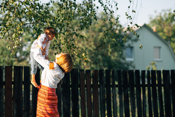 Family: mother carries a boy. They are dressed in embroidered robes.