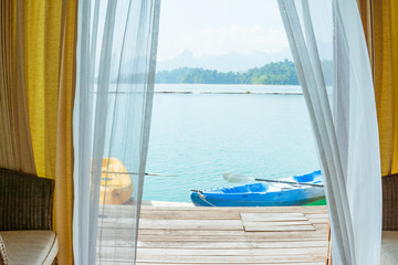 Fototapeta na wymiar Landscape view through window with curtain and kayak boat, travelling vacation and relaxing background concept.