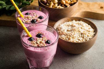 Glasses of berry smoothie with nuts, mint, blueberry, blackberry, raspberry, and yogurt on wooden table. Weight loss and diet concept. 
