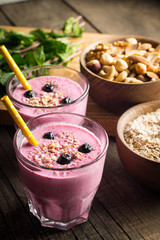 Glasses of berry smoothie with nuts, mint, blueberry, blackberry, raspberry, and yogurt on wooden table. Weight loss and diet concept. 