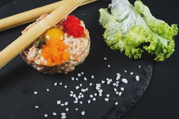 Tartar with caviar and bread sticks on black