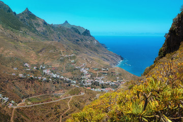 Taganana village with white houses and serpentine road in green Anaga mountain  in Tenerife, Canary Islands. Spain. Taganana valley and Atlantic ocean landscape background.