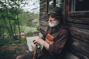 Naklejka premium old bearded forester with axe near wooden hut