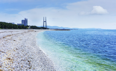 Naklejka premium Beautiful artificial marble beach along the shoreline of Rinku Town viewing green pines and Tajiri Sky Bridge , Osaka , Japan