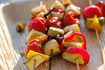 Grilled vegetable skewers in a herb marinade on a wooden plate, onion pepper zucchini tomato roasted barbecue