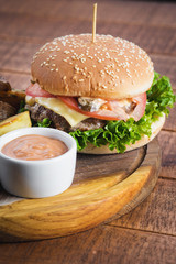 Tasty burger with fried potatoes on wooden board