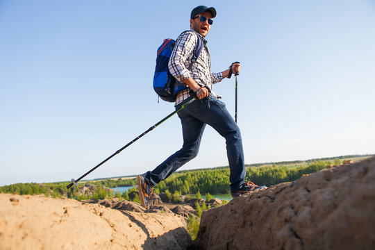 Picture of tourist man with walking sticks walking in mountainous area