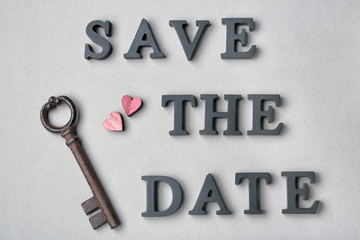 Vintage key and phrase SAVE THE DATE composed with letters on grey background