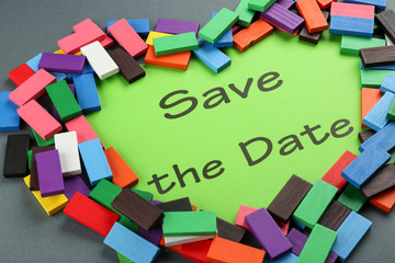 Heart made of colorful blocks with text "Save the Date" on sheet of paper on grey background