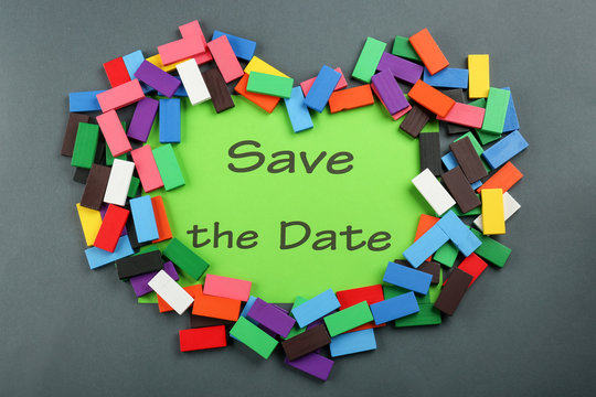 Heart made of colorful blocks with text "Save the Date" on sheet of paper on grey background
