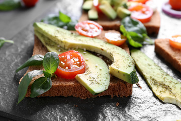Delicious toast with avocado on slate plate, closeup