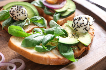 Delicious toasts with avocado on wooden board, closeup