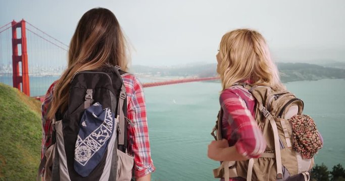 White females backpacking in San Francisco enjoying the view of the Golden Gate Bridge, Rear view of 2 young ladies in San Francisco looking at the Golden Gate Bridge, 4k