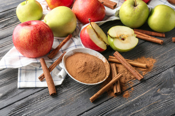 Fresh apples, cinnamon sticks and powder on wooden table