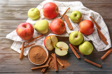 Fresh apples, cinnamon sticks and powder on wooden table