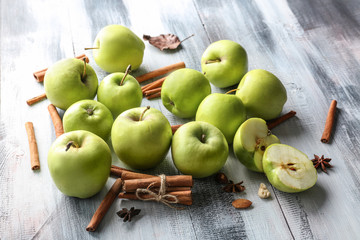 Fresh apples and cinnamon sticks on wooden background