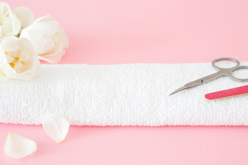 Scissors and nails file on the white towel. Care about women's hands or feet nails. Manicure, pedicure beauty salon. Beautiful roses on pink table. Fresh flowers. Empty place for text or logo.