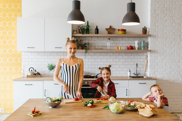 Photo of beautiful woman with her daughter cutting vegetables in kitchen