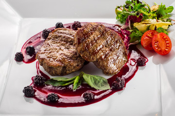Grilled meat steak with raspberrie sauce on wooden background