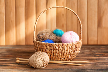 Wicker basket with knitting yarn and needles on table
