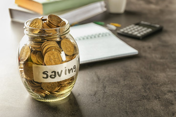 Jar for savings full of coins on table