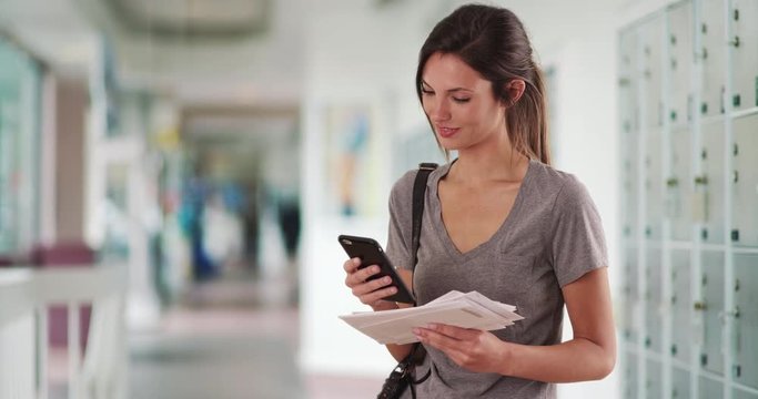 Woman with mail checking smartphone and walking offscreen in post office hall, Millennial Caucasian girl holding letters texting on phone by parcel lockers, 4k