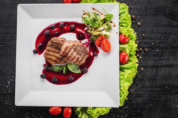 Grilled meat steak with raspberrie sauce on wooden background