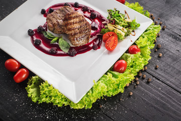 Grilled meat steak with raspberrie sauce on wooden background
