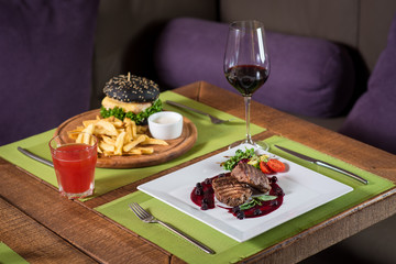 Grilled meat steak with raspberrie sauce on wooden background